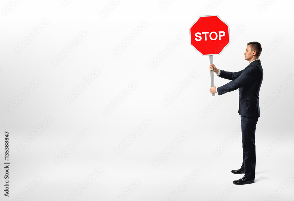 Businessman standing on white background and holding a stop sign. Businessman standing on white background and holding a stop sign.