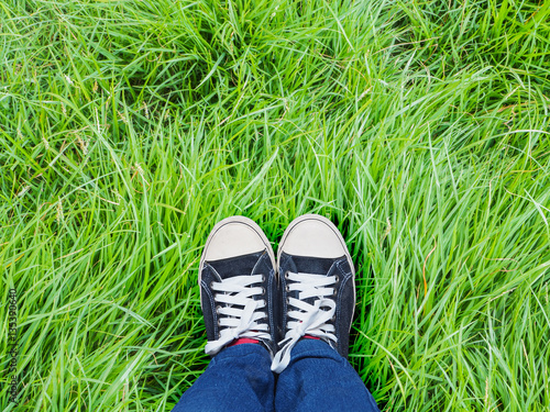Selfie feet wearing sneaker shoes on green grass background