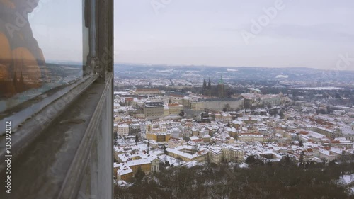 Tourist Looking at the Snowy City of Prague and Castle from Above (Petrin Tower) photo