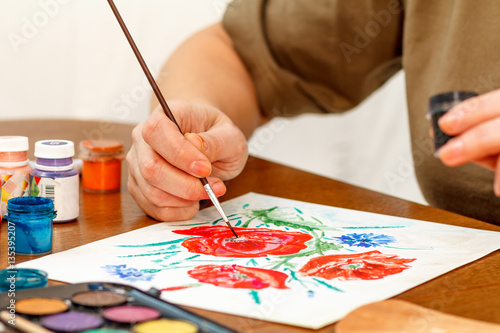 Woman's hand painting poppy flowers