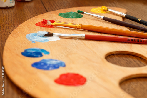 Wooden palette with laying on paints and paintbrushes