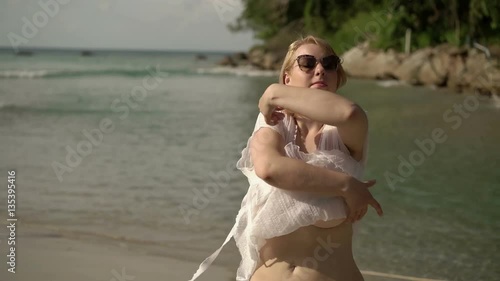 Young blonde sexy woman undressing on a beach