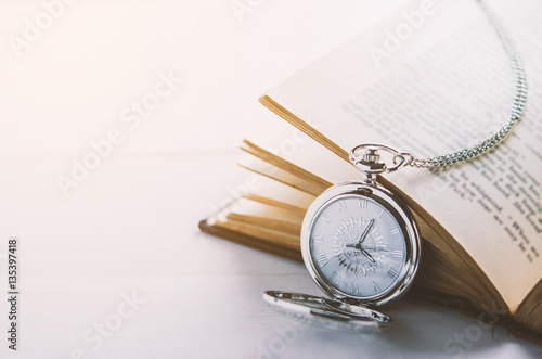 Close up of antique silver pocket watch and opened book