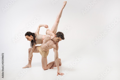 Elegant young ballet dancers performing in the white colored studio