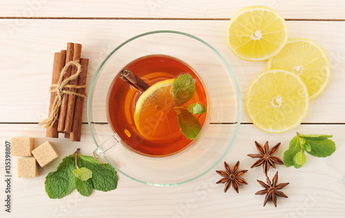 tea in a transparent mug with lemon and cinnamon and mint leaves