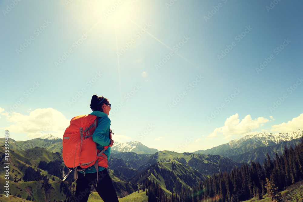 young woman backpacker hiking on forest mountain peak