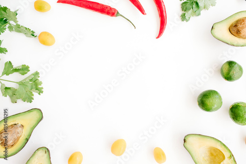 Frame made of raw food ingredients of guacamole: avocado, chili pepper, coriander, cherry tomato, lime. Flat lay, top view. Food concept.