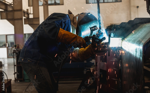 Man welding factory in the dark dim.