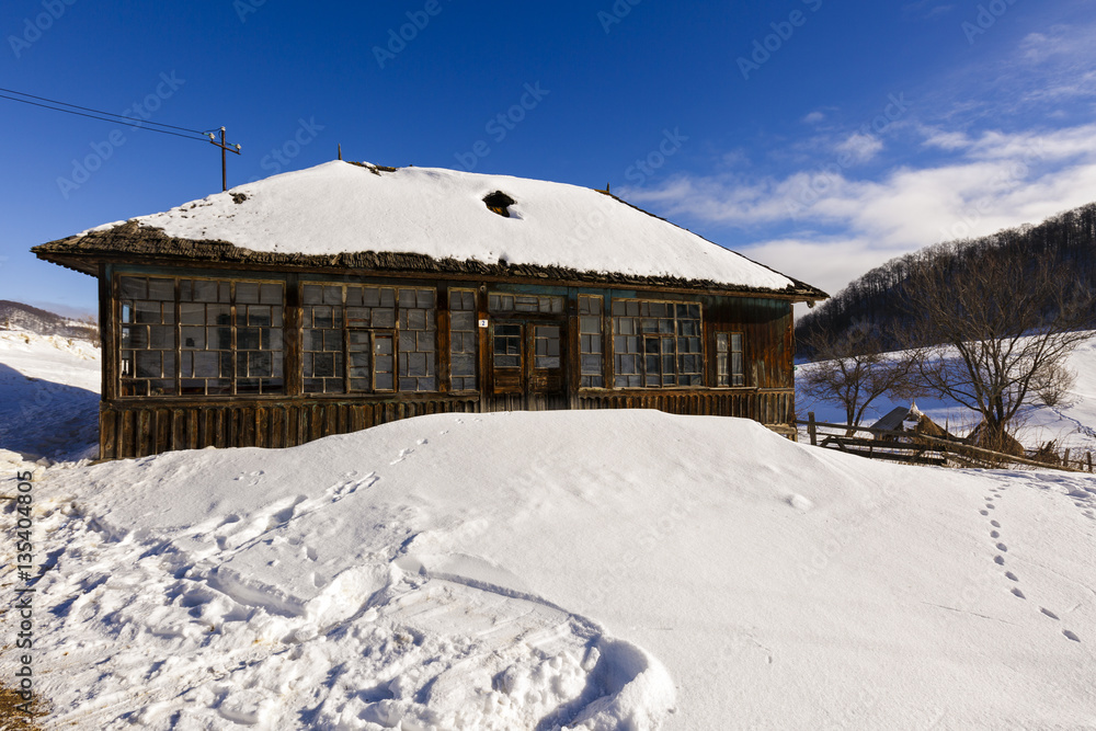 Old wooden house in winter landscape, Romania