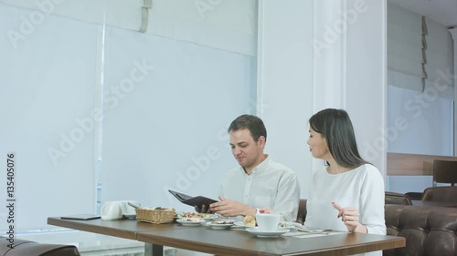 Happy couple paying bill brought by waiter and leaving cafe