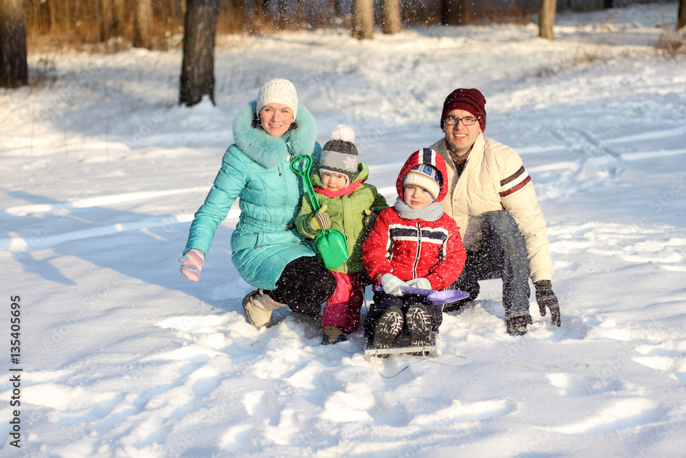 family of four has fun in the snow in winter