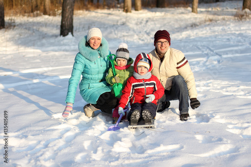 family of four has fun in the snow in winter