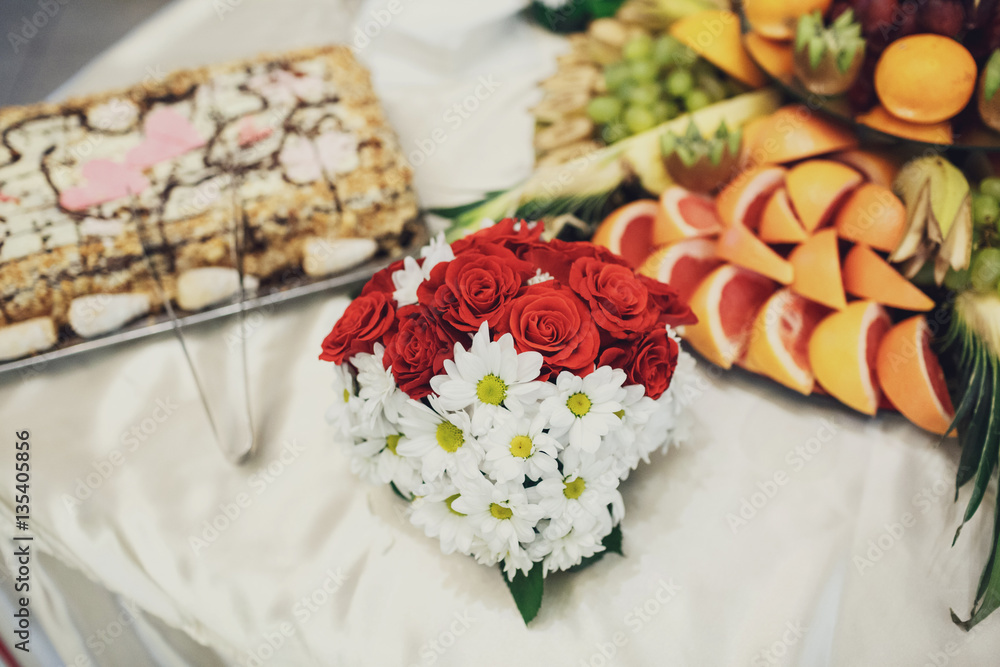 Little bouquet of red and white flowers stands before plate with Little bouquet of red and white flowers stands before plate with