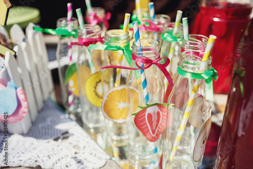 Paper fruits pinned on glass bottles stand on the buffet