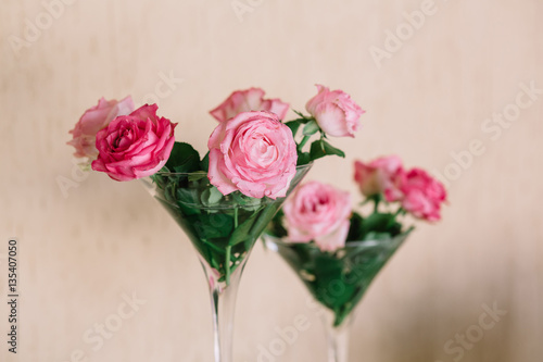 Tall vases in form of cocktail glasses and pink roses in them