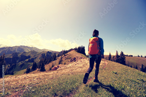 young woman backpacker hiking on forest mountain peak