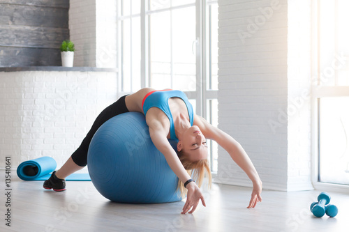 Woman exercising her abs on a Pilates ball. Natural light. Shallow DOF.