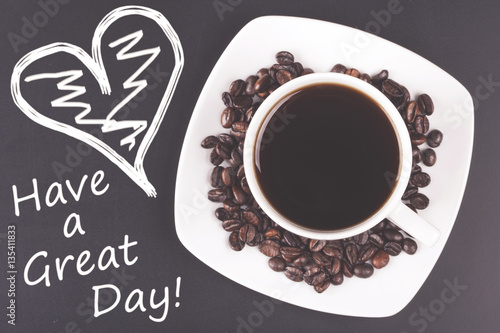 Cup of coffee with have a great day message. Table top view