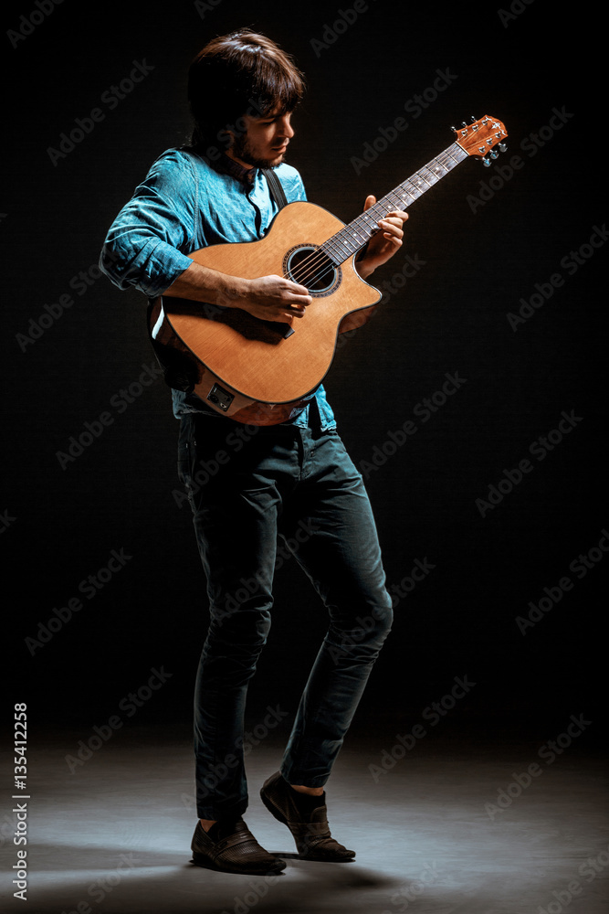 Cool guy standing with guitar on dark background