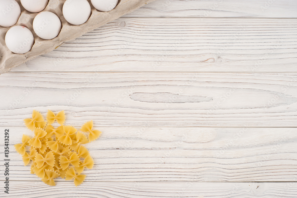 Pasta and eggs in a tray on an old white wooden table. Pasta and eggs in a tray on an old white wooden table.