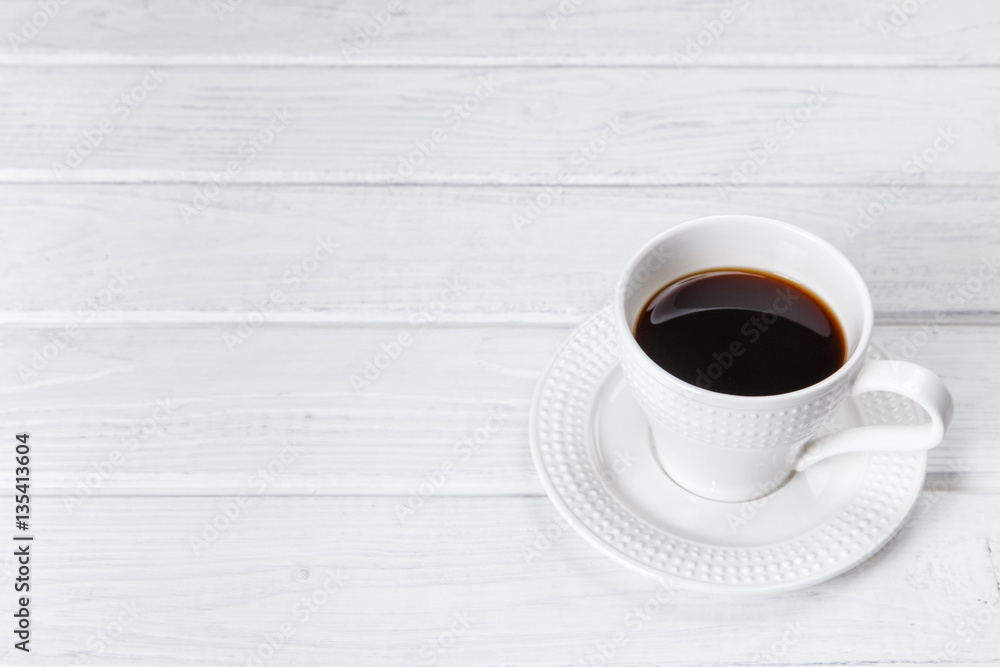 White mug of coffee on a white wooden background. Space for text. White mug of coffee on a white wooden background. Space for text.