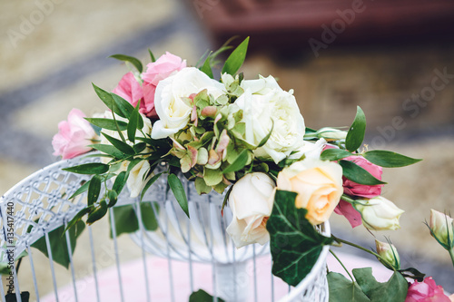 Pink and white roses put on the top of bird cage