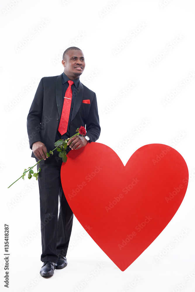 African man in black suite holding red rose. African man in black suite holding red rose.