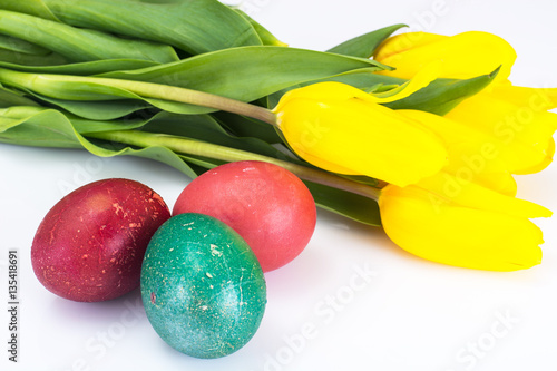 Easter painted eggs and bunch of tulips on a white