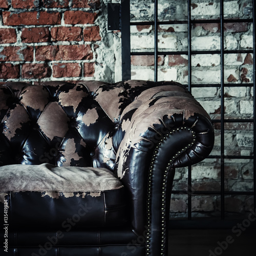 Old vintage sofa on background of brick wall and grids, selectiv photo