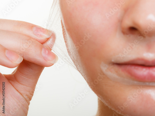 Woman removing facial peel off mask closeup