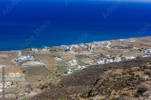 A view of vineyards with white architecture with blue sea in background on Santorini island, Greece