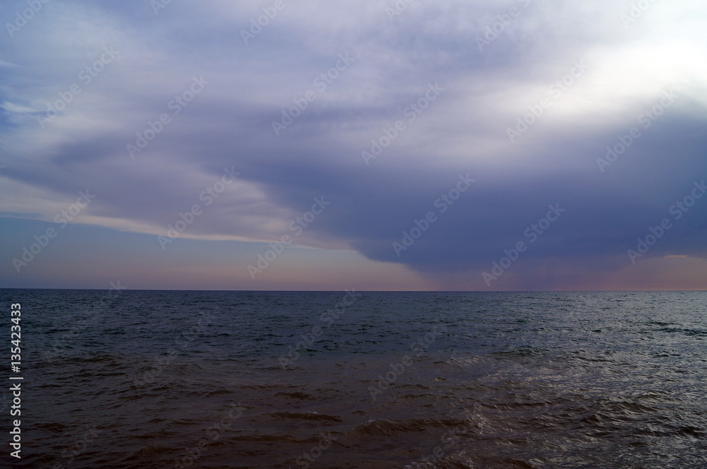 Dark clouds over the calm waters of the sea at sunset