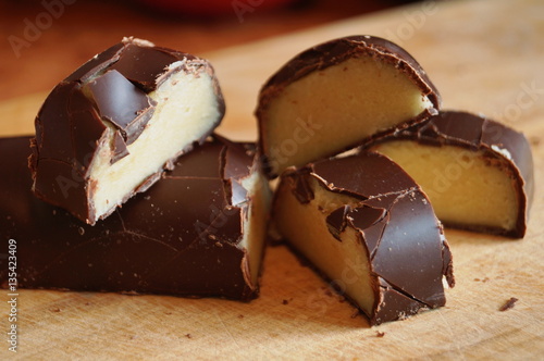Candy with a marzipan covered with chocolate on a wooden table
