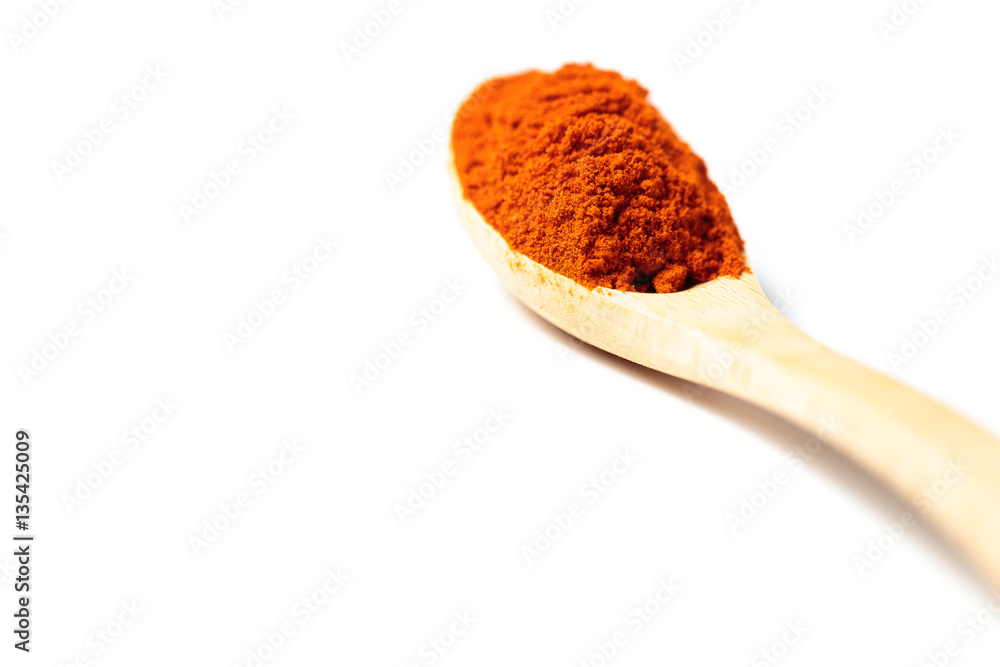Chili powder in a wooden spoon isolated over white background Chili powder in a wooden spoon isolated over white background
