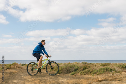 handsome man in casual outfit ride a mountain bike on island