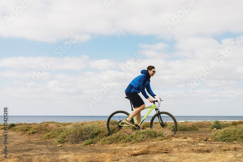 handsome man  in casual outfit ride a mountain bike on island © very_ulissa