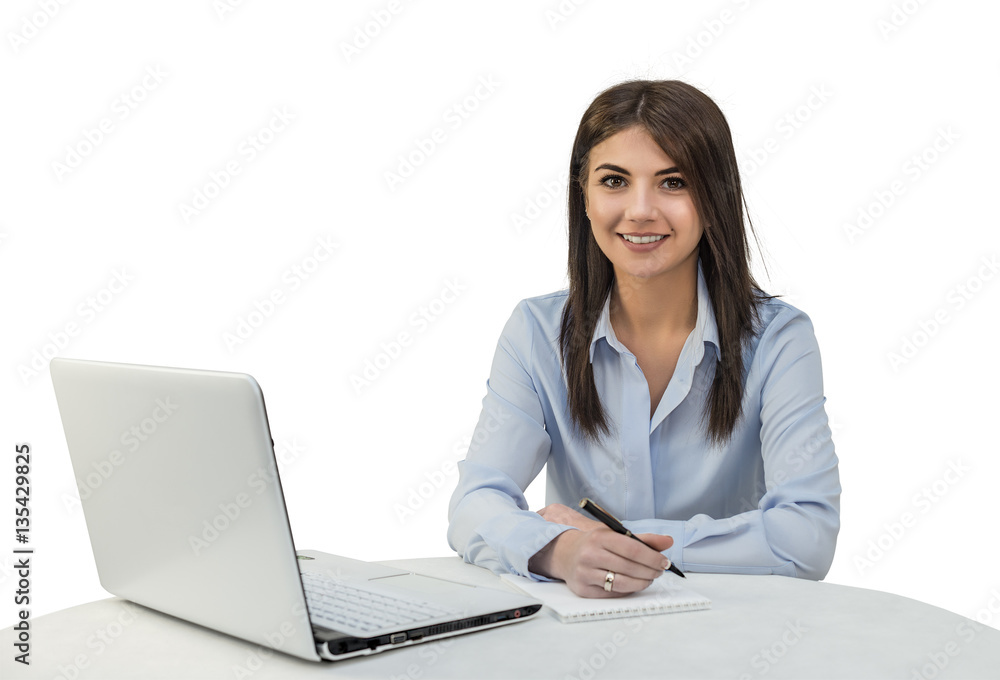 A young pretty girl sitting in the office with a laptop, pen and notepad. White isolated background. A young pretty girl sitting in the office with a laptop, pen and notepad. White isolated background.