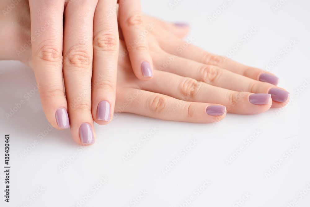 Closeup of hands of a young woman with pink manicure on nails against white background Closeup of hands of a young woman with pink manicure on nails against white background