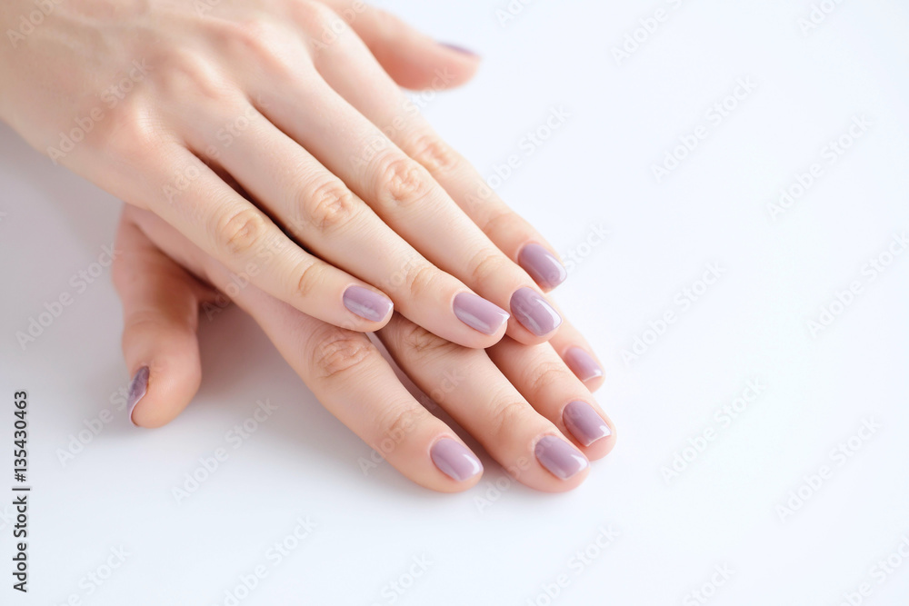 Closeup of hands of a young woman with pink manicure on nails against white background