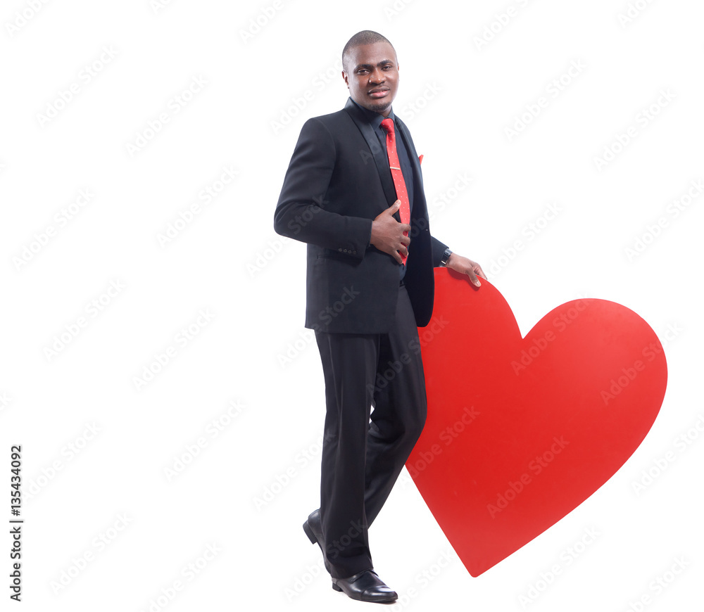 African man in black suite leaning on big red heart. African man in black suite leaning on big red heart.