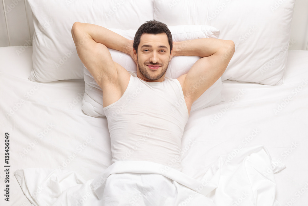 Handsome man lying in bed and looking at the camera Handsome man lying in bed and looking at the camera