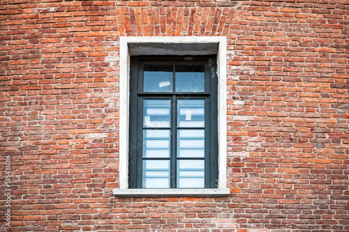Window with black frame in old brick wall