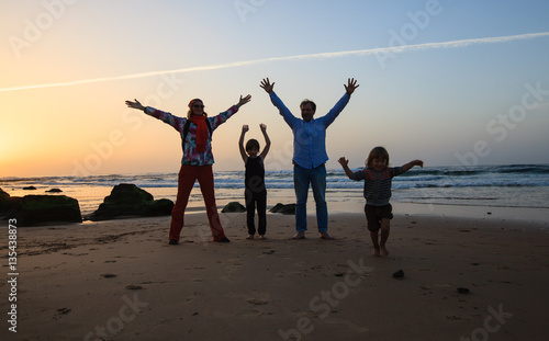 Happy family of four have fun oon beach in Algarve, Portugal. Mother, father and two kids boy have holiday
