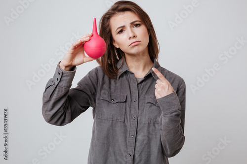 Sick young woman pointing to enema. photo