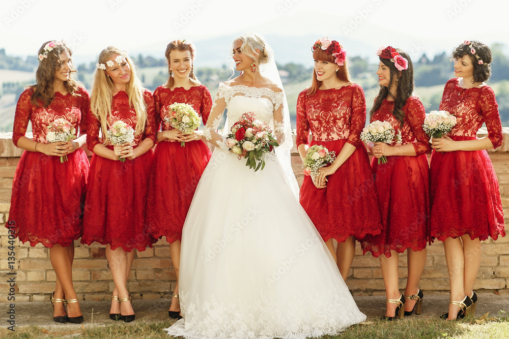 Stunning blonde bride and bridesmaids in short red dresses pose