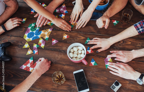Top view creative photo of friends sitting at wooden table.  having fun while playing board game photo