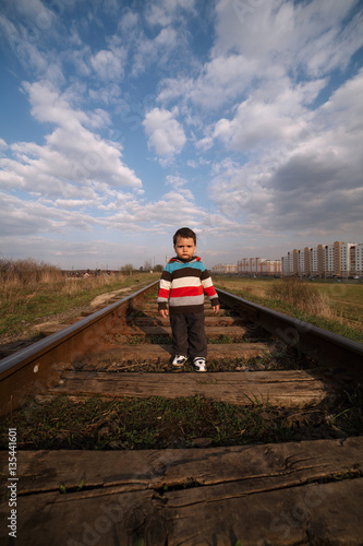 little beautiful boy plays on railroad