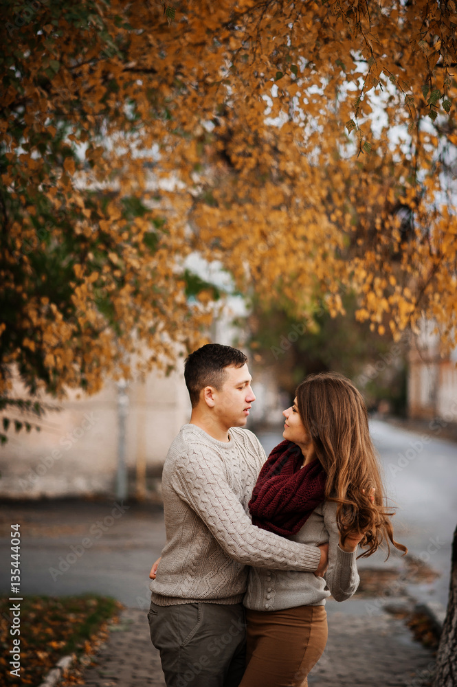 Young couple wearing on tied warm sweaters hugging in love at ci Young couple wearing on tied warm sweaters hugging in love at ci