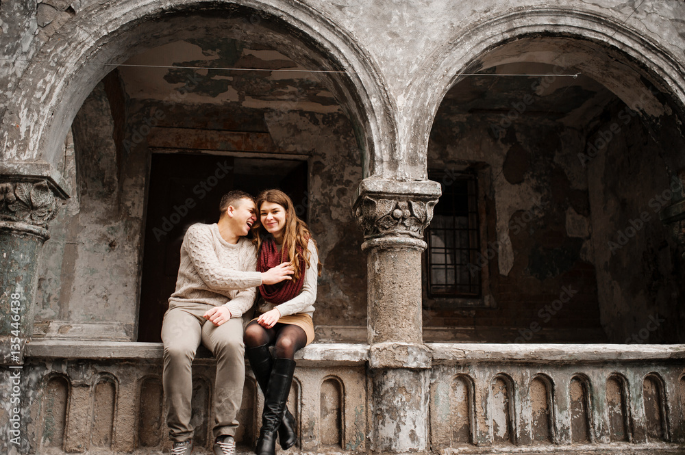 Young couple wearing on tied warm sweaters in love sitting on st Young couple wearing on tied warm sweaters in love sitting on st