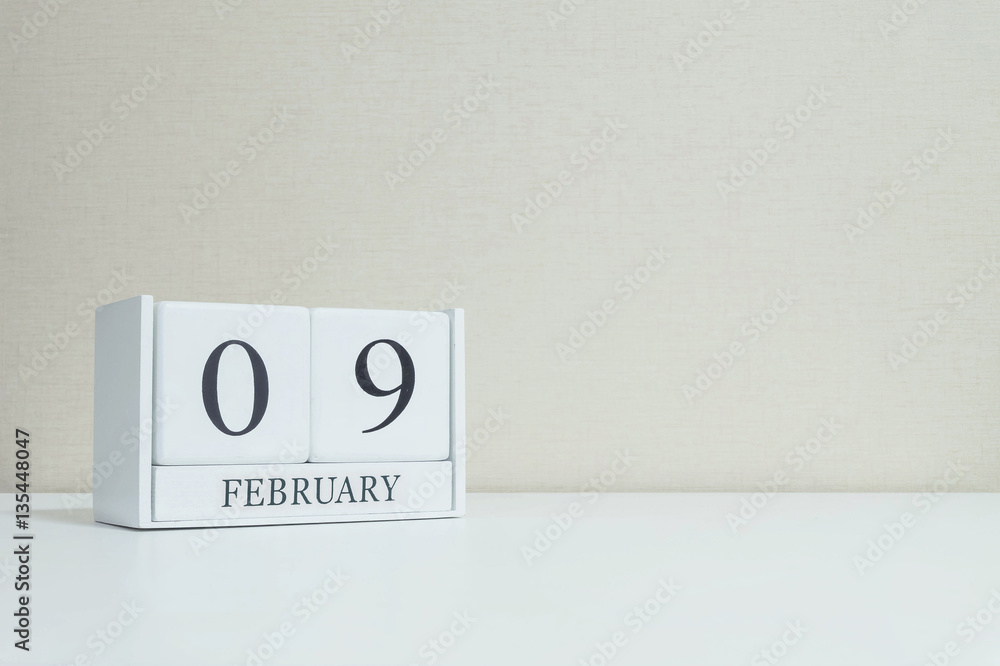 Closeup white wooden calendar with black 9 february word on blurred white wood desk and cream color wallpaper in room textured background with copy space in selective focus at the calendar Closeup white wooden calendar with black 9 february word on blurred white wood desk and cream color wallpaper in room textured background with copy space in selective focus at the calendar